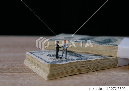 Miniature figures shaking hands on cash. 120727702