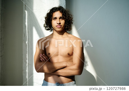 Portrait of topless serious handsome man with crossed arms illumed with daylight standing still for photo Portrait of topless serious handsome man with crossed arms illumed with daylight standing still for photo 120727986