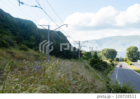Train tracks stretch through the Armenian landscape beneath a bright sky filled with fluffy clouds 120728511