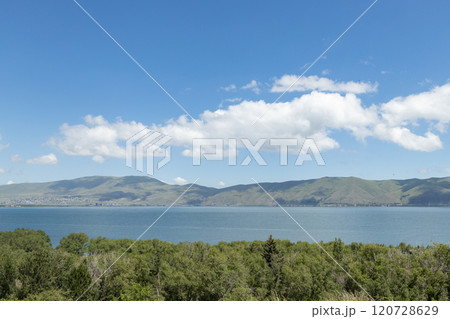 Peaceful waters of Sevan lake reflecting the serene Armenian landscape beneath a bright blue sky Peaceful waters of Sevan lake reflecting the serene Armenian landscape beneath a bright blue sky 120728629