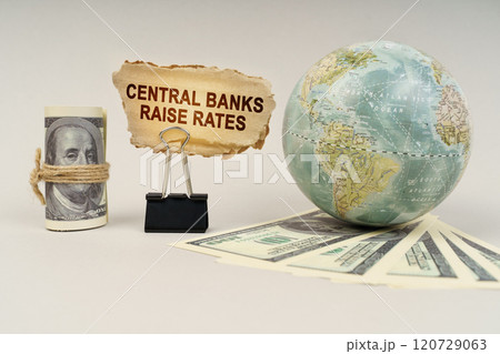 On the table are dollars, a globe and there is a sign with the inscription - Central banks raise rates On the table are dollars, a globe and there is a sign with the inscription - Central banks raise rates 120729063