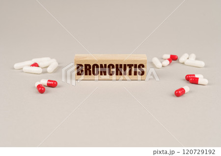 On a gray surface are tablets, capsules and a wooden plate with the inscription - Bronchitis On a gray surface are tablets, capsules and a wooden plate with the inscription - Bronchitis 120729192
