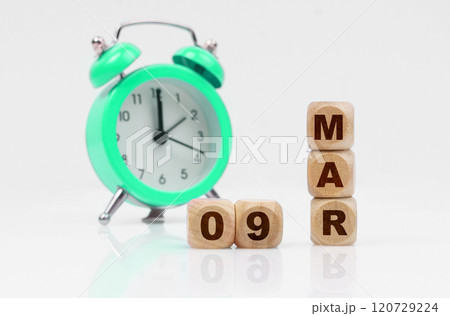 On a white background, a green alarm clock and a calendar with the inscription - March 9 120729224