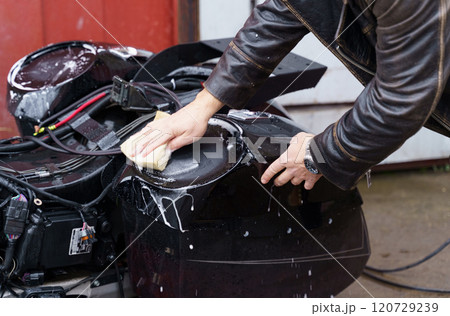 Washing a motorcycle with a high pressure jet. 120729239