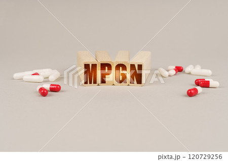 On a gray surface are pills and a red wooden block with the inscription - MPGN On a gray surface are pills and a red wooden block with the inscription - MPGN 120729256