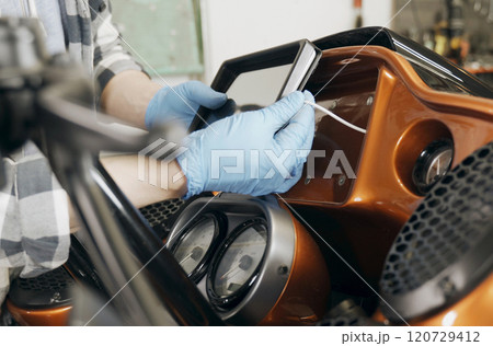 The mechanic installs a tablet on a motorcycle. 120729412