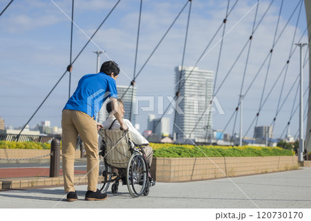 屋外で車椅子を押す介護スタッフ 120730170