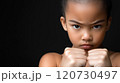 A young girl stands confidently with her fists clenched, exhibiting concentration and determination 120730497