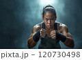 A determined athlete prepares for an intense training session in a dimly lit gym 120730498