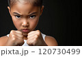 A determined young girl practicing martial arts with a focused expression against a dark background 120730499