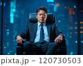 A businessman in a suit sits confidently in a high-rise office at night with city lights glowing 120730503