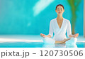 Woman meditating by a serene pool in daylight, fostering mindfulness and relaxation 120730506
