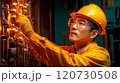 A technician inspects control panels in an industrial facility during evening hours 120730508