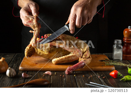 In a warm, dimly lit kitchen, hands expertly carve a beautifully roasted duck. Fresh herbs and spices add vibrant colors and aromas, enhancing the culinary atmosphere In a warm, dimly lit kitchen, hands expertly carve a beautifully roasted duck. Fresh herbs and spices add vibrant colors and aromas, enhancing the culinary atmosphere 120730513