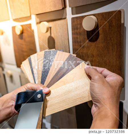 Designer hand picking sample of wood laminated from natural collection in material showroom Designer hand picking sample of wood laminated from natural collection in material showroom 120732386