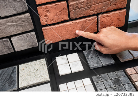 Architect hand pointing at brick pattern with stone tile collection display on sample board 120732395