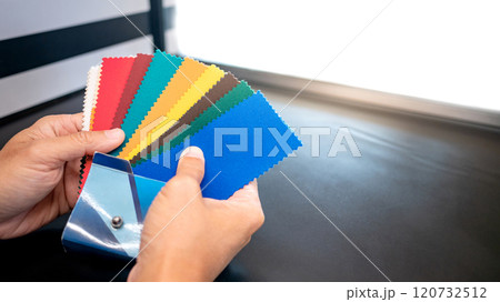 Fabric swatch material choice. Designer hand choosing fabric sample pieces from color collection Fabric swatch material choice. Designer hand choosing fabric sample pieces from color collection 120732512