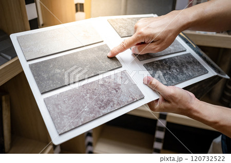 Flooring material design collection. Designer hand pointing at stone tile sample on display catalog 120732522