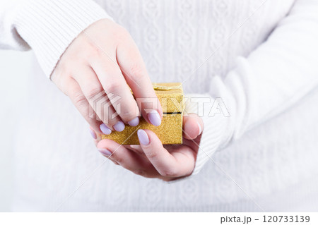 Female hands open a yellow gift box. 120733139