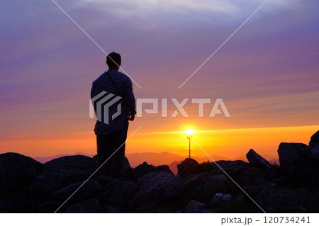 朝日連峰の以東岳山頂から夕陽を眺める登山者 朝日連峰の以東岳山頂から夕陽を眺める登山者 120734241