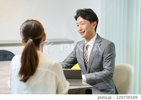 女性に向かって話すスーツ姿の男性 120736509