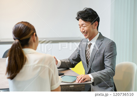 女性に向かって話すスーツ姿の男性 120736510