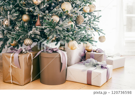 Decorated Christmas tree with frosted branches and wrapped presents, gift boxes it in living room Decorated Christmas tree with frosted branches and wrapped presents, gift boxes it in living room 120736598
