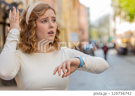 Redhead woman worrying to be punctual with anxiety checking time on watch running late to work Redhead woman worrying to be punctual with anxiety checking time on watch running late to work 120736742