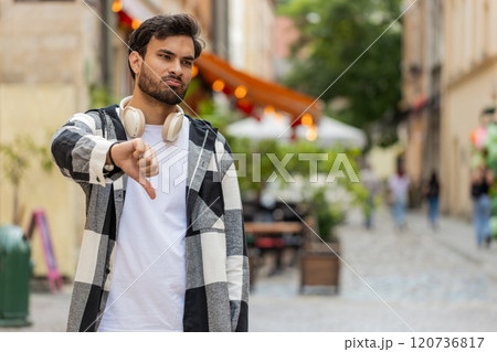 Upset Indian man showing thumb down sign gesture, expressing discontent disapproval in city street 120736817
