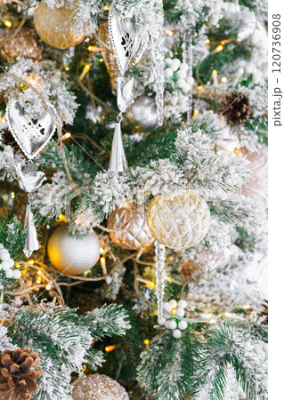 Christmas tree with frosted snowy branches decorated with silver and gold ornaments with lights 120736908