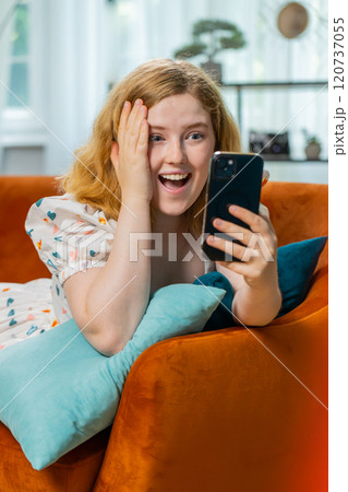 Happy redhead woman at home use smartphone typing browsing wow yes found out great big win celebrate Happy redhead woman at home use smartphone typing browsing wow yes found out great big win celebrate 120737055