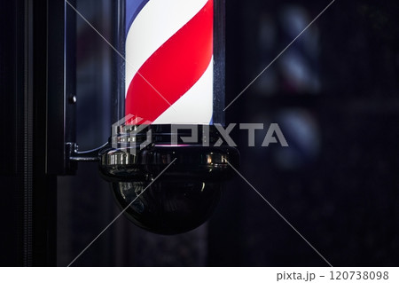 Vintage barber pole illuminated at night showcasing classic design features 120738098