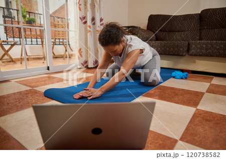 Woman practicing yoga at home with online class 120738582