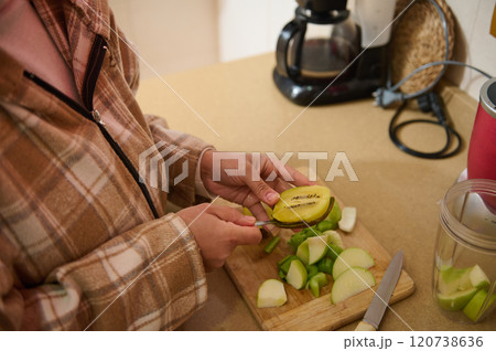 Woman preparing kiwi and green apple on kitchen counter Woman preparing kiwi and green apple on kitchen counter 120738636