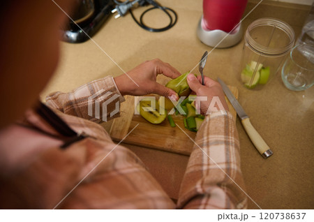 Person preparing fresh kiwi for a healthy smoothie Person preparing fresh kiwi for a healthy smoothie 120738637