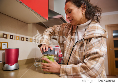 Woman preparing healthy green smoothie in modern kitchen Woman preparing healthy green smoothie in modern kitchen 120738648