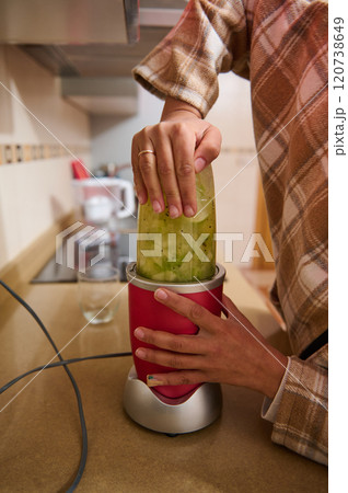 Person blending fresh green smoothie in a modern kitchen 120738649
