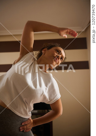 Woman practicing side stretch exercise in cozy indoor setting 120739470