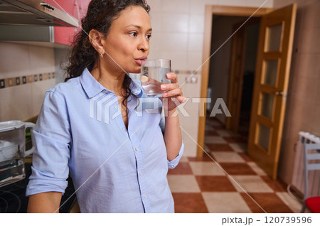 Woman in kitchen drinking a refreshing glass of water Woman in kitchen drinking a refreshing glass of water 120739596