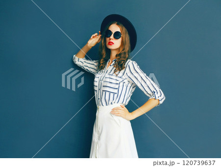 Fashion portrait elegant woman wearing black glasses, hat and white skirt posing on gray background Fashion portrait elegant woman wearing black glasses, hat and white skirt posing on gray background 120739637