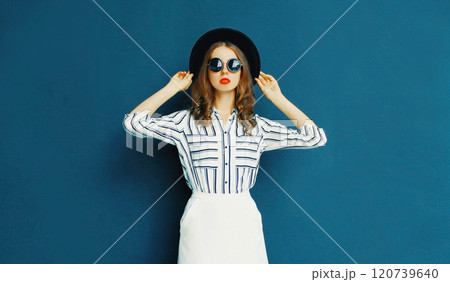 Fashion pretty elegant woman wearing a black glasses, hat and white skirt posing on gray background Fashion pretty elegant woman wearing a black glasses, hat and white skirt posing on gray background 120739640