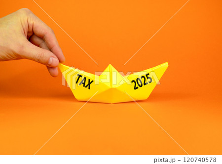 Planning tax 2025 new year symbol. Concept words Tax 2025 on beautiful yellow paper boat. Beautiful orange paper background. Businessmen hand. Business tax 2025 new year concept. Copy space. Planning tax 2025 new year symbol. Concept words Tax 2025 on beautiful yellow paper boat. Beautiful orange paper background. Businessmen hand. Business tax 2025 new year concept. Copy space. 120740578