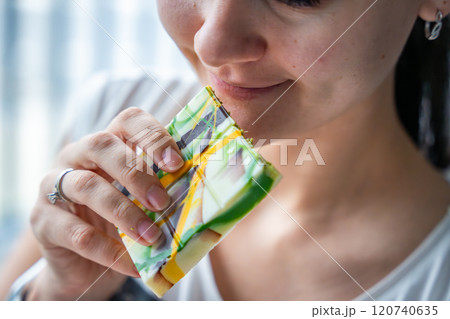 Woman eating trend Dubai white chocolate with pistachio paste and kataifi dough. Confectionery handmade sweets at home in the kitchen.  120740635
