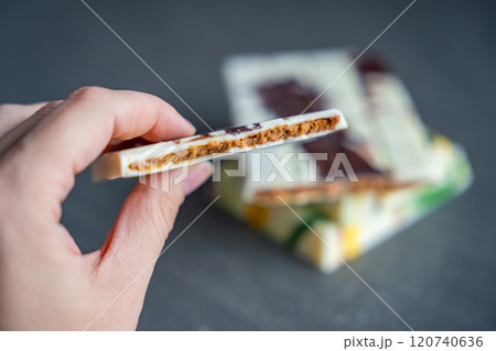 Piece of trend Dubai white chocolate with halva paste in woman hand. Confectionery handmade sweets at home in the kitchen.  120740636