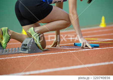 Runner preparing at starting blocks for a relay race during a track event 120740656