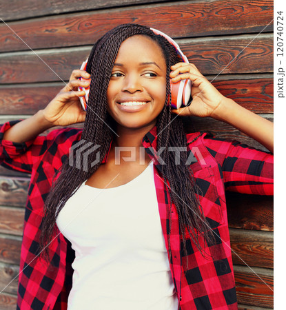 Fashion portrait happy smiling young african woman in headphones is enjoying listens to music Fashion portrait happy smiling young african woman in headphones is enjoying listens to music 120740724