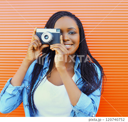 Portrait of happy smiling african woman with old vintage camera over red background Portrait of happy smiling african woman with old vintage camera over red background 120740752