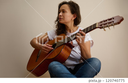 Woman playing acoustic guitar in relaxed home setting Woman playing acoustic guitar in relaxed home setting 120740775
