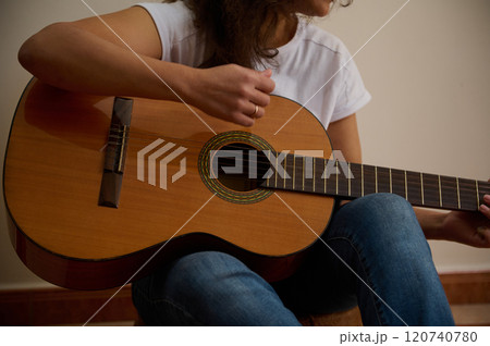 Woman playing a classical guitar in casual setting 120740780