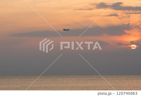 Airplane flying over the sea with a colorful sunset in the background Airplane flying over the sea with a colorful sunset in the background 120740863